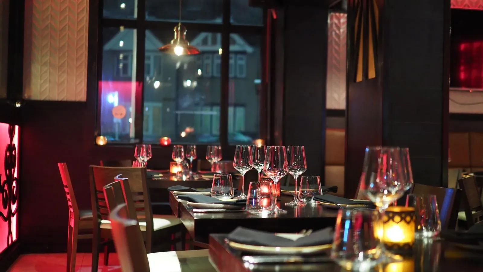 Sala di un ristorante apparecchiata, vista dalla vetrina che dà sulla strada